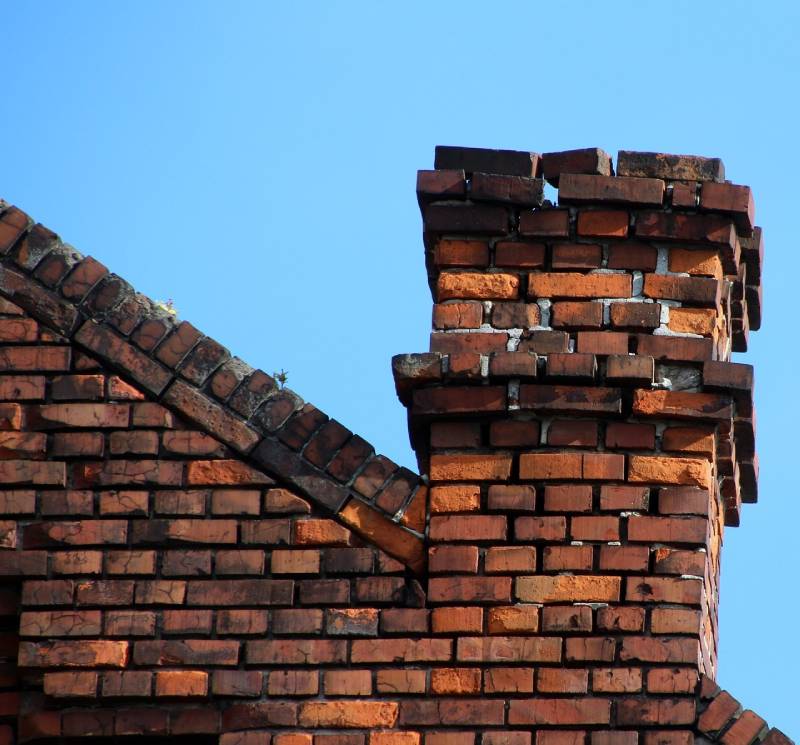 Damaged chimney on an Lansing home showing cracks and missing mortar